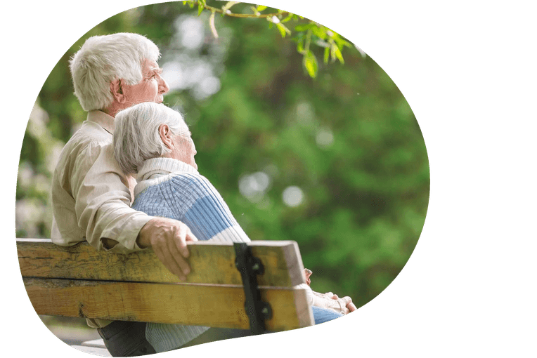 An elderly couple sitting together on a bench